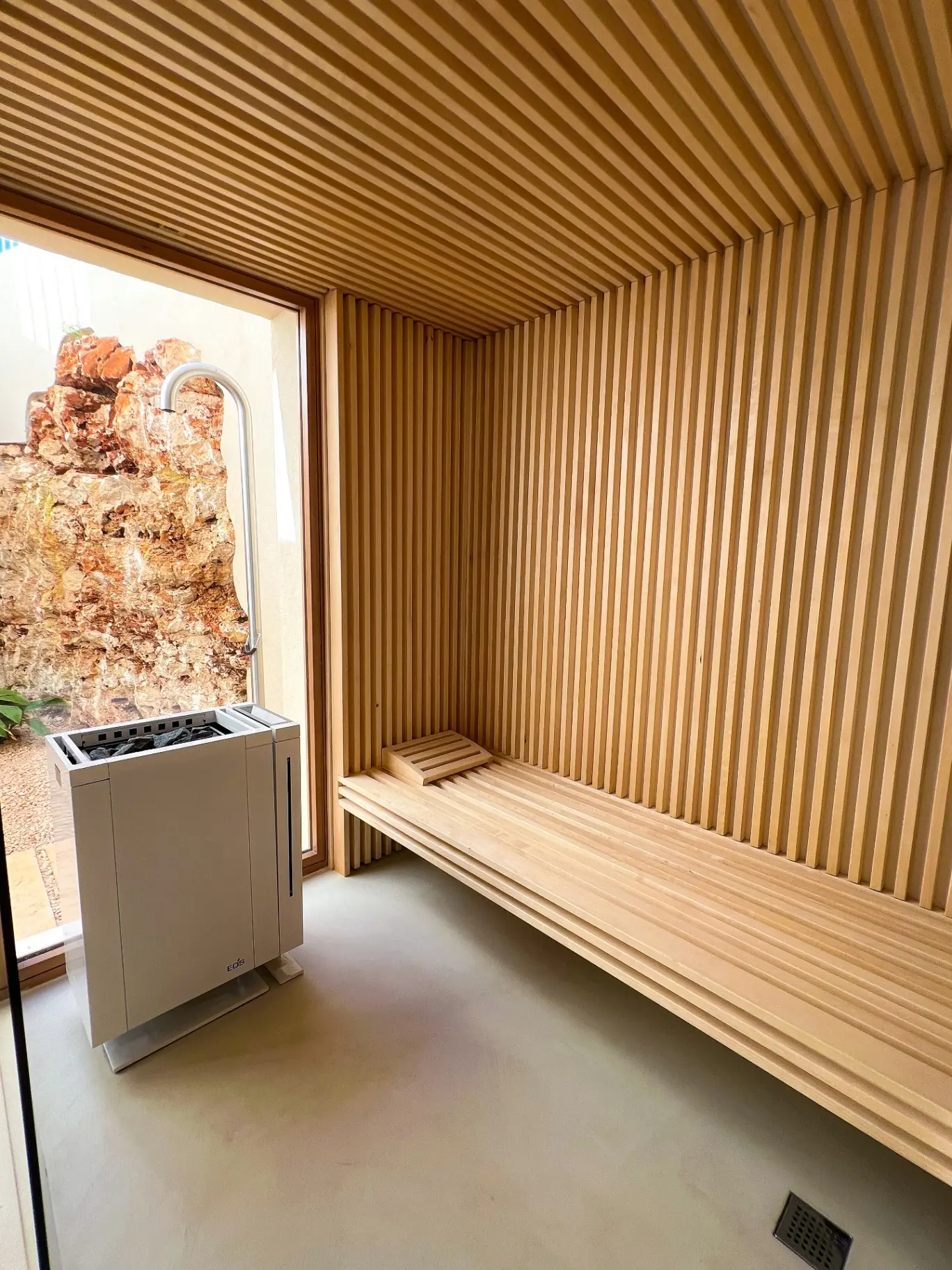 Sauna with timber slats and view of the natural stone wall